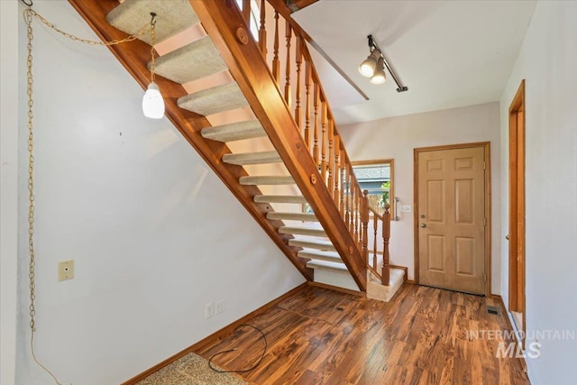 foyer entrance with stairway, wood finished floors, and baseboards