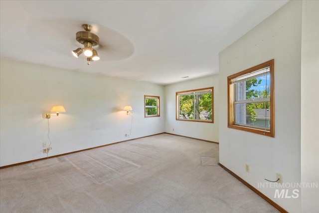 empty room featuring healthy amount of natural light, a ceiling fan, carpet floors, and baseboards
