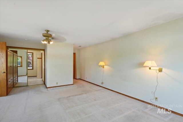 unfurnished room featuring a ceiling fan, light colored carpet, and baseboards