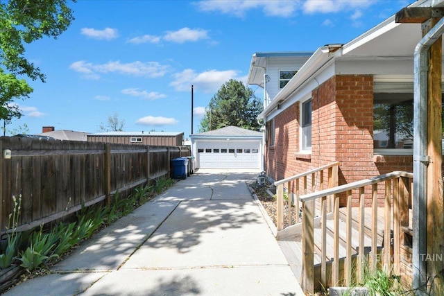view of home's exterior featuring brick siding, a detached garage, an outdoor structure, and fence