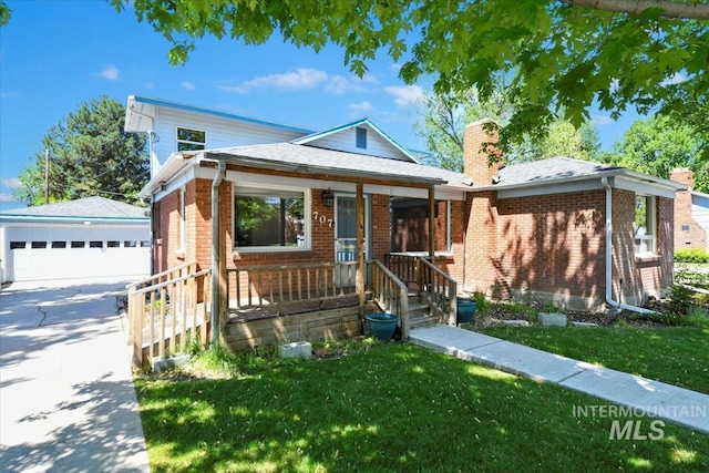view of front of property with a chimney, brick siding, a detached garage, an outbuilding, and covered porch