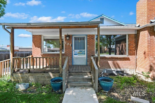 view of front of house with brick siding, covered porch, and a chimney