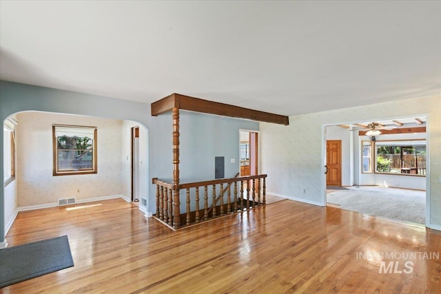 living area with arched walkways, wood finished floors, a ceiling fan, and baseboards
