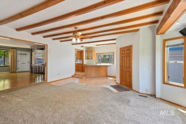 unfurnished living room with light colored carpet, baseboards, beam ceiling, and a ceiling fan