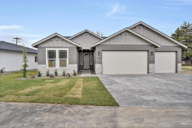 view of front facade featuring driveway, stone siding, board and batten siding, a front yard, and an attached garage