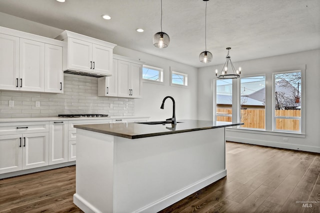 kitchen with a healthy amount of sunlight, dark wood-style floors, backsplash, and a sink