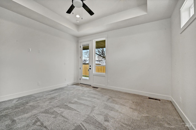 unfurnished room featuring baseboards, a raised ceiling, light colored carpet, and ceiling fan