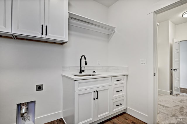 laundry room with electric dryer hookup, a sink, dark wood-style floors, cabinet space, and baseboards