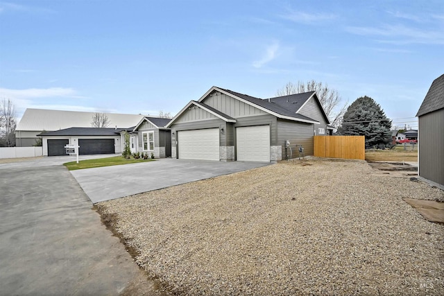 view of front of property with driveway, an attached garage, board and batten siding, and fence