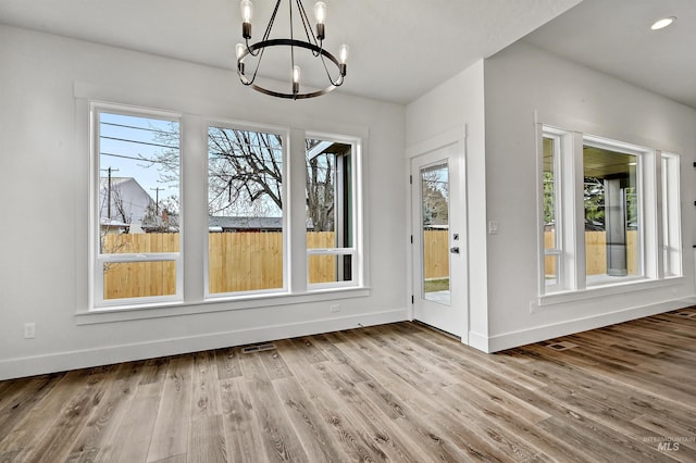 unfurnished dining area featuring visible vents, a notable chandelier, wood finished floors, recessed lighting, and baseboards