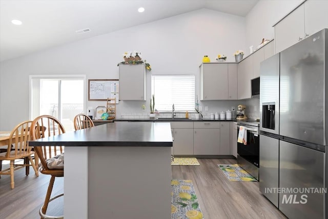 19339 Susquehanna Way, Caldwell, ID 83605 - kitchen with stainless steel appliances, dark countertops, a sink, dark wood finished floors, and a kitchen bar