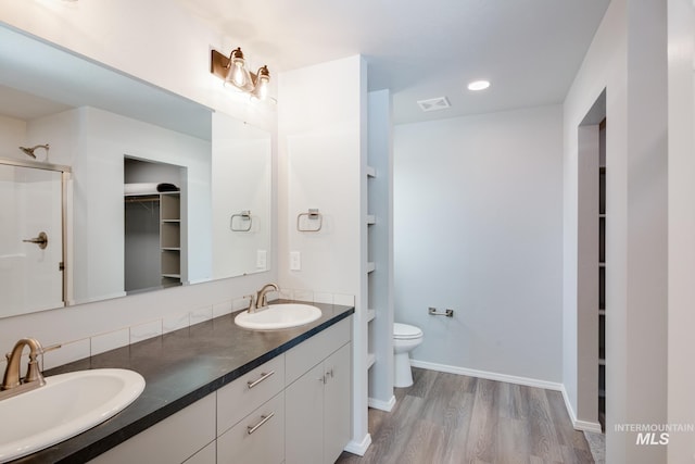 19339 Susquehanna Way, Caldwell, ID 83605 - bathroom with a walk in closet, double vanity, toilet, wood finished floors, and a stall shower