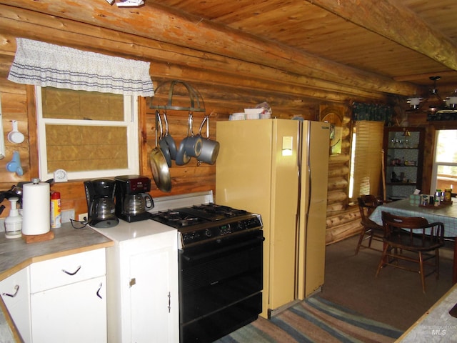 3695 W Mountain Rd, Anatone, WA 99401 - kitchen with gas stove, rustic walls, wooden ceiling, white cabinets, and freestanding refrigerator