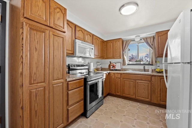 kitchen featuring decorative backsplash, sink, and white appliances