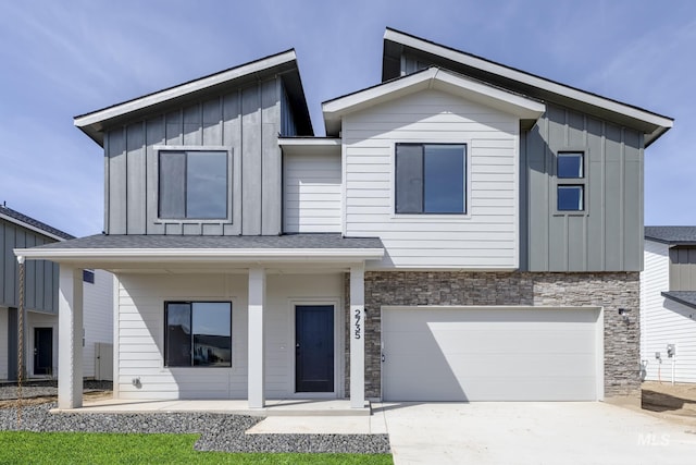 view of front facade featuring concrete driveway, an attached garage, stone siding, and board and batten siding