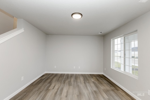 unfurnished room with baseboards, visible vents, and wood finished floors