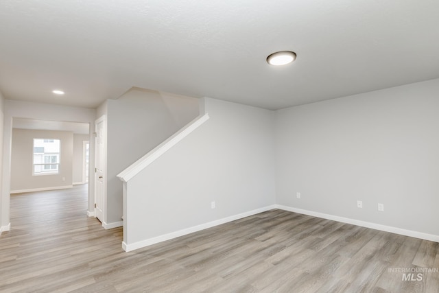 spare room featuring stairs, baseboards, light wood-type flooring, and recessed lighting