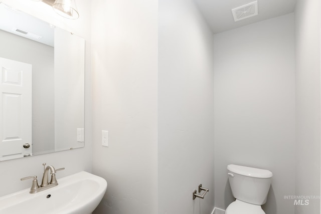 bathroom featuring toilet, visible vents, and a sink