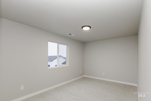 spare room featuring light colored carpet and baseboards