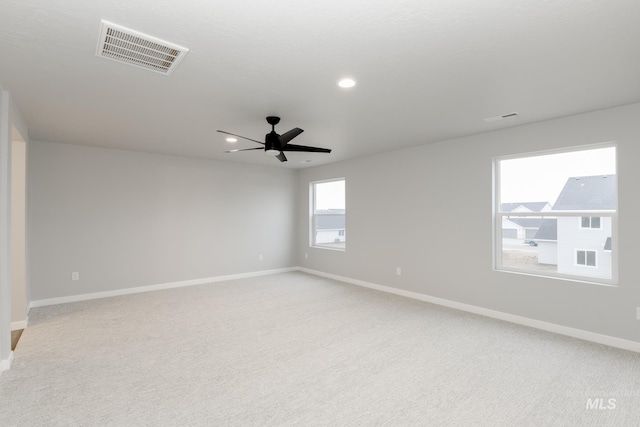 spare room with baseboards, light carpet, visible vents, and a ceiling fan