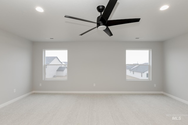 spare room with light colored carpet, baseboards, a ceiling fan, and a healthy amount of sunlight