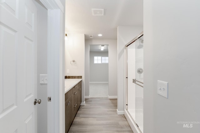 full bathroom with baseboards, visible vents, a shower stall, vanity, and wood finished floors
