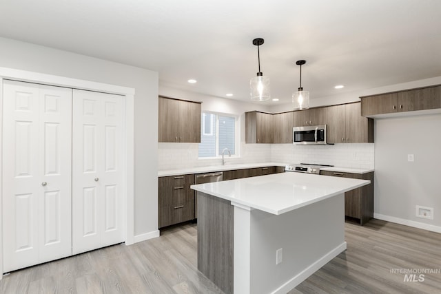 kitchen with stainless steel appliances, backsplash, light wood-type flooring, and modern cabinets