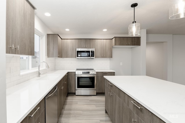 kitchen featuring a sink, stainless steel appliances, light wood-type flooring, modern cabinets, and light countertops