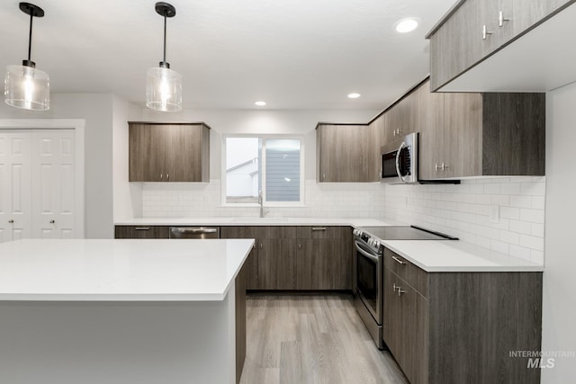 kitchen featuring light countertops, stainless steel appliances, modern cabinets, and a sink