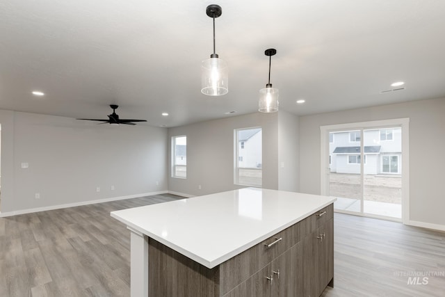 kitchen featuring light countertops, light wood-style floors, a kitchen island, and baseboards