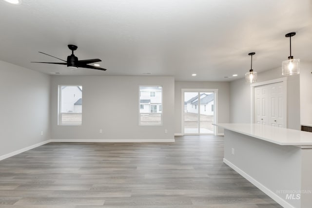 unfurnished living room with wood finished floors, baseboards, a ceiling fan, and recessed lighting