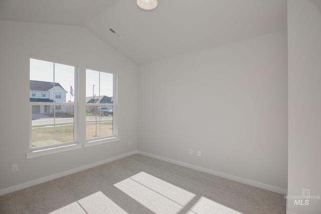 empty room featuring visible vents, baseboards, a residential view, vaulted ceiling, and light carpet