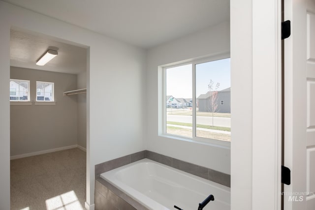 full bath featuring a bath and baseboards