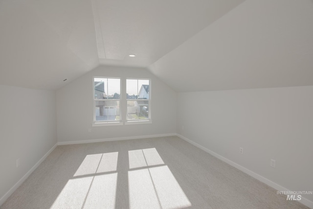 bonus room featuring baseboards, lofted ceiling, and light carpet