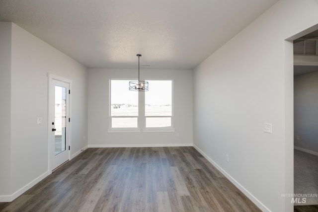 unfurnished dining area with an inviting chandelier, dark wood-type flooring, baseboards, and visible vents