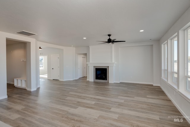 unfurnished living room with visible vents, light wood finished floors, baseboards, recessed lighting, and a fireplace