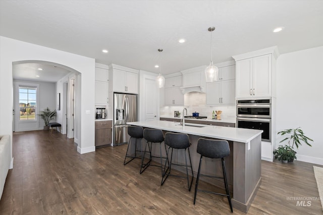 6086 S Sachet Ave, Meridian, ID 83642 - kitchen with appliances with stainless steel finishes, light countertops, arched walkways, a breakfast bar area, and recessed lighting