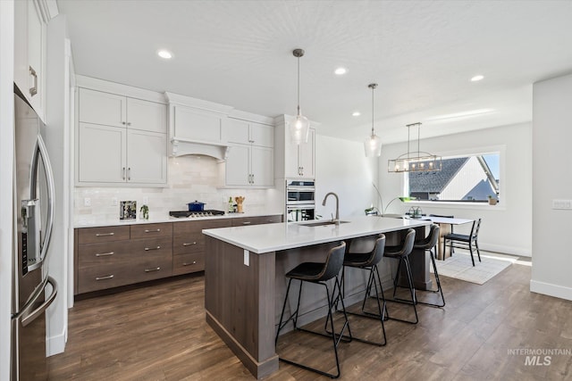 6086 S Sachet Ave, Meridian, ID 83642 - kitchen featuring decorative backsplash, a breakfast bar area, light countertops, white cabinets, and stainless steel appliances