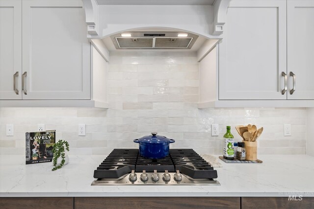 6086 S Sachet Ave, Meridian, ID 83642 - kitchen featuring stainless steel gas cooktop, white cabinetry, ventilation hood, light stone counters, and arched walkways