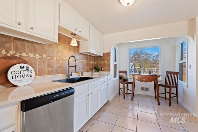 kitchen with white cabinetry, sink, stainless steel dishwasher, backsplash, and light tile patterned flooring