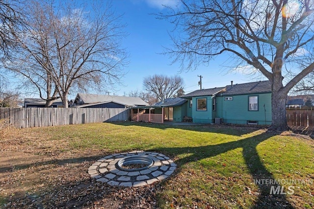 view of front of home featuring a front yard, an outdoor fire pit, and central air condition unit