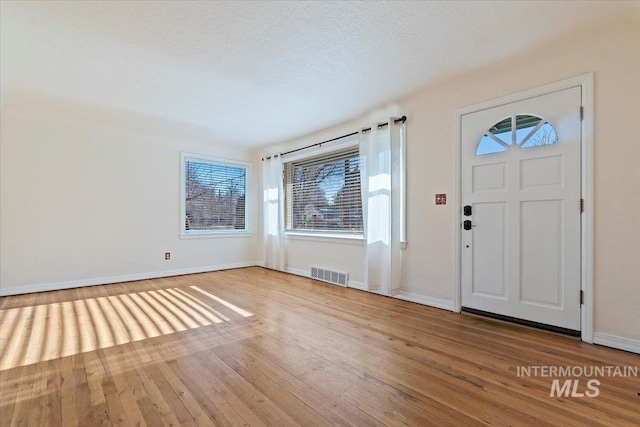 entryway with a textured ceiling and light hardwood / wood-style flooring