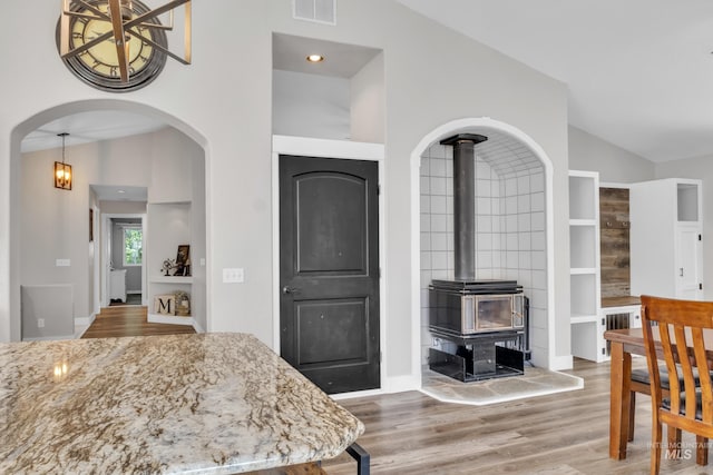 8466 W Idaho Blvd, Letha, ID 83636 - dining area featuring a wood stove, lofted ceiling, wood finished floors, arched walkways, and built in shelves