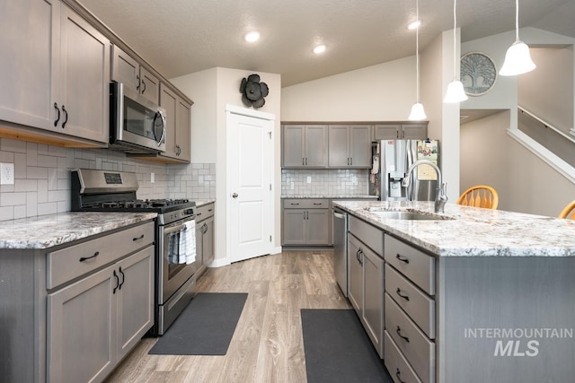 kitchen featuring lofted ceiling, appliances with stainless steel finishes, gray cabinetry, and a sink