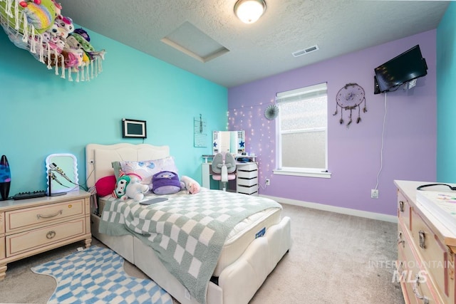 bedroom featuring attic access, light carpet, a textured ceiling, visible vents, and baseboards