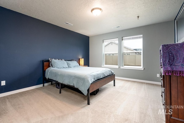 bedroom with baseboards, visible vents, a textured ceiling, and light colored carpet