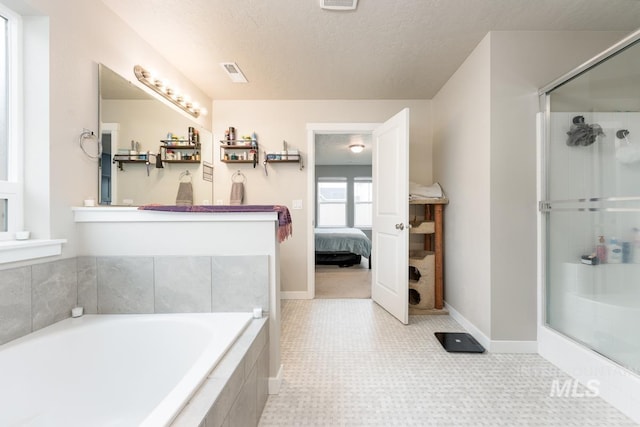ensuite bathroom with a shower stall, a textured ceiling, and baseboards