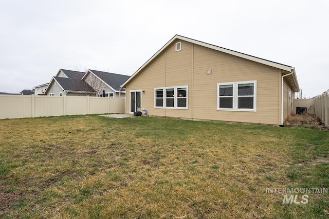 rear view of property with a lawn and a fenced backyard