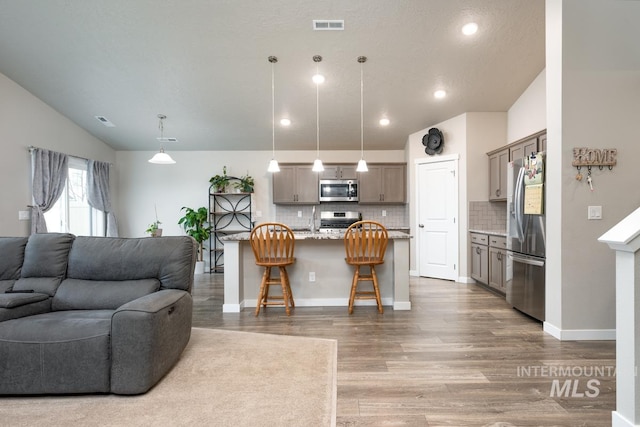 living room featuring recessed lighting, vaulted ceiling, wood finished floors, and visible vents