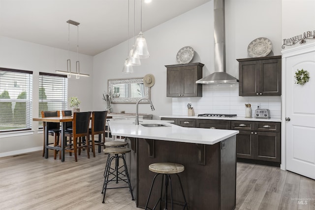 1010 Blueridge Dr, Kimberly, ID 83341 - kitchen with wall chimney range hood, light countertops, a kitchen bar, stainless steel gas stovetop, and light wood-style flooring